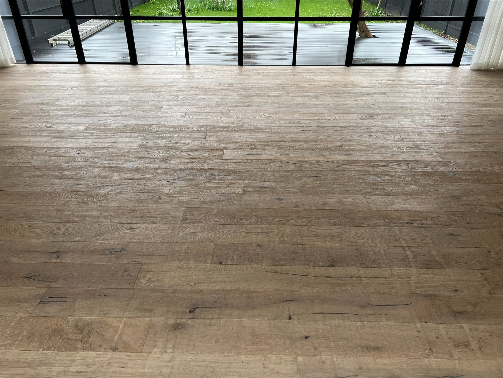 Worn European oak plank floor before professional wood floor sanding, showing a dull, scratched surface awaiting restoration.