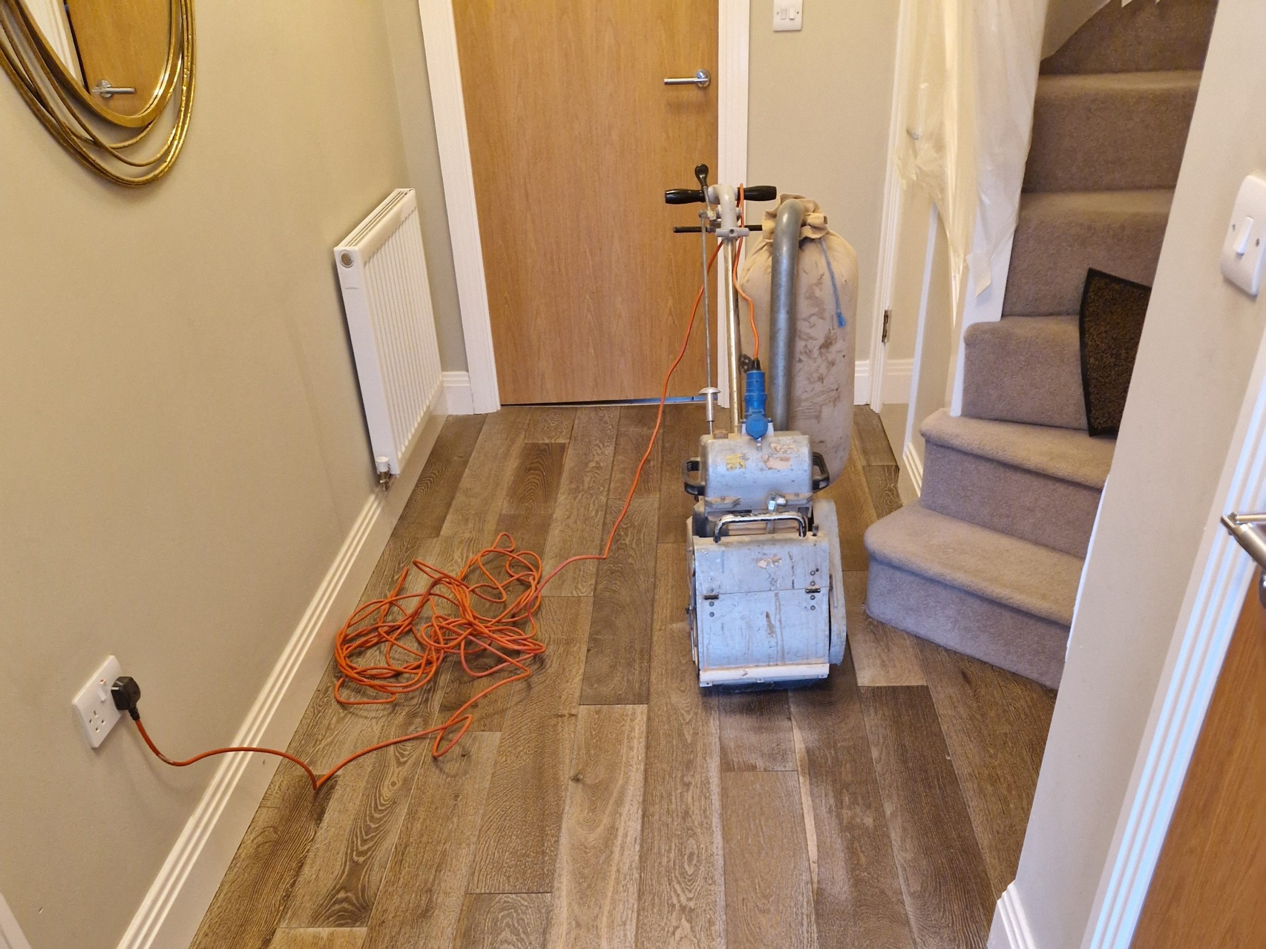 Wood Floor Sanding Setup – Smoked Oak Plank Hallway Floor Wood floor sanding machine in a narrow hallway, ready to refinish a smoked oak plank floor during professional restoration.