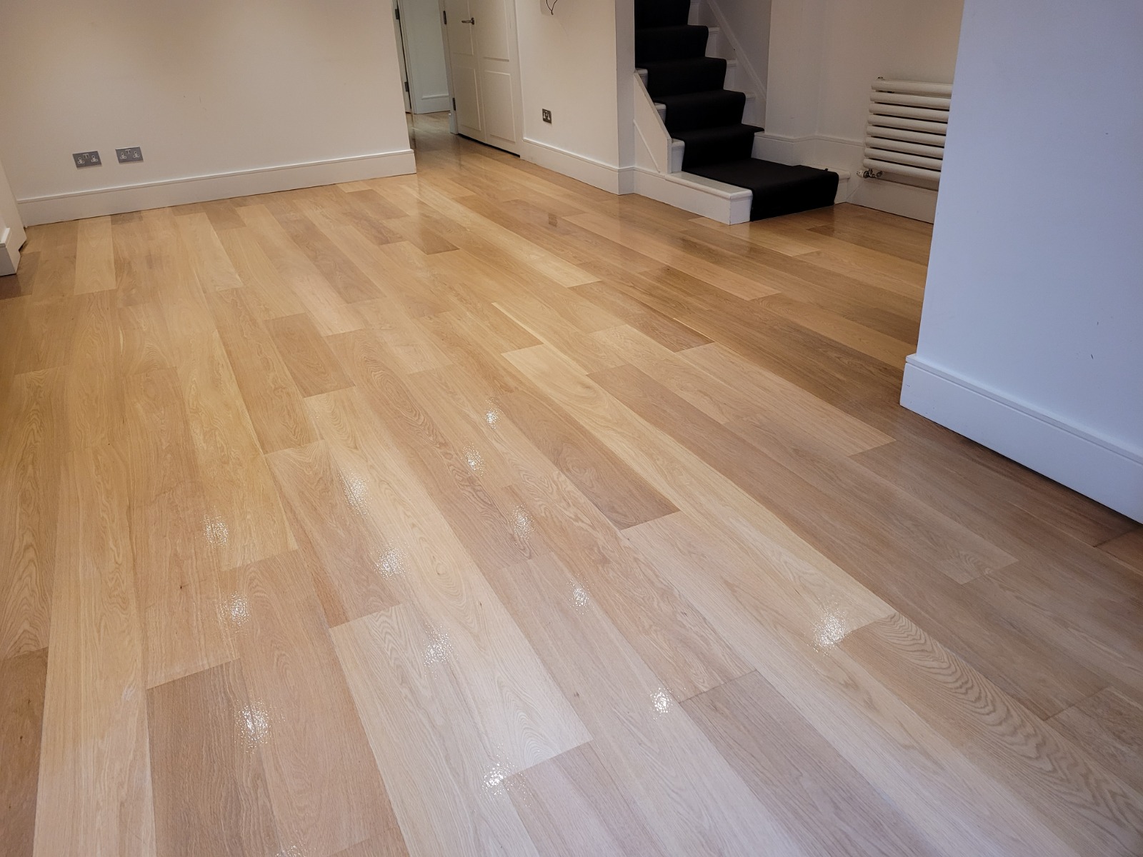 Wood Floor Sanding in New Southgate on engineered oak plank flooring, freshly refinished to a satin-matt lacquer with an even, reflective sheen.