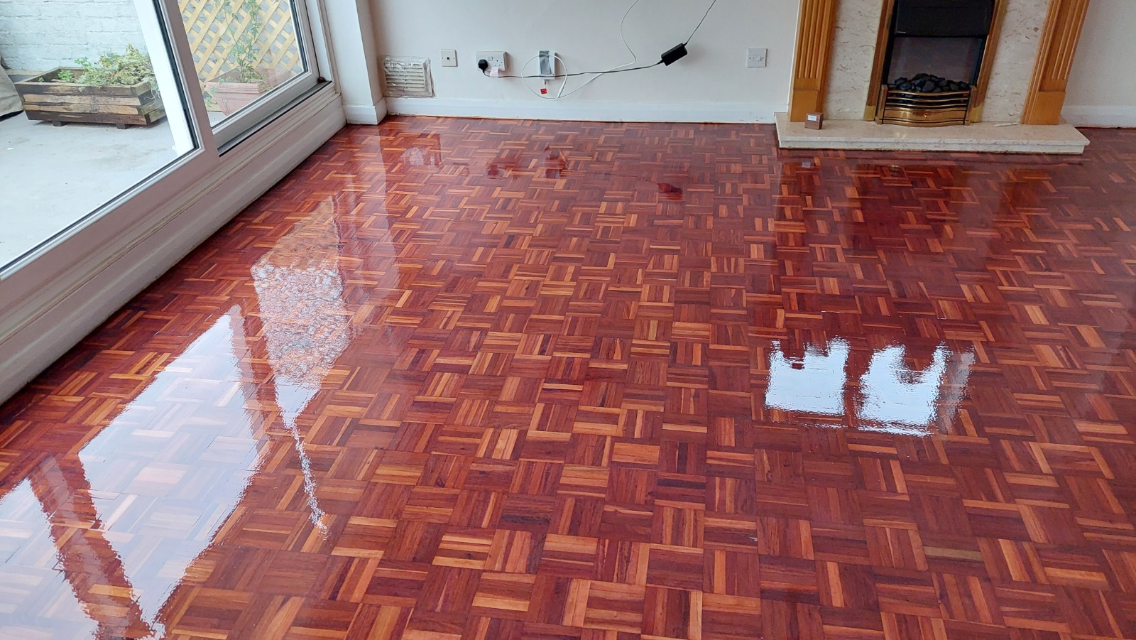 Wood Floor Sanding in New Southgate on a reddish hardwood parquet block floor, fully refinished with a deep gloss in a bright living room.