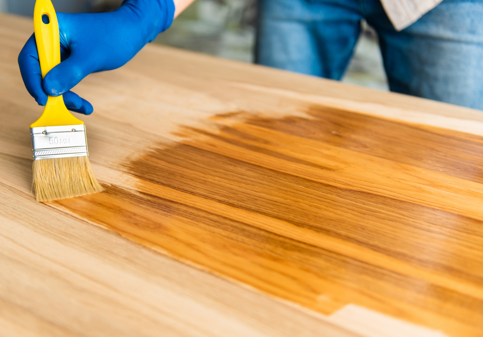 Wood Floor Sanding in New Southgate with stain being brushed onto a freshly sanded solid oak hardwood floor, enriching the grain and colour.